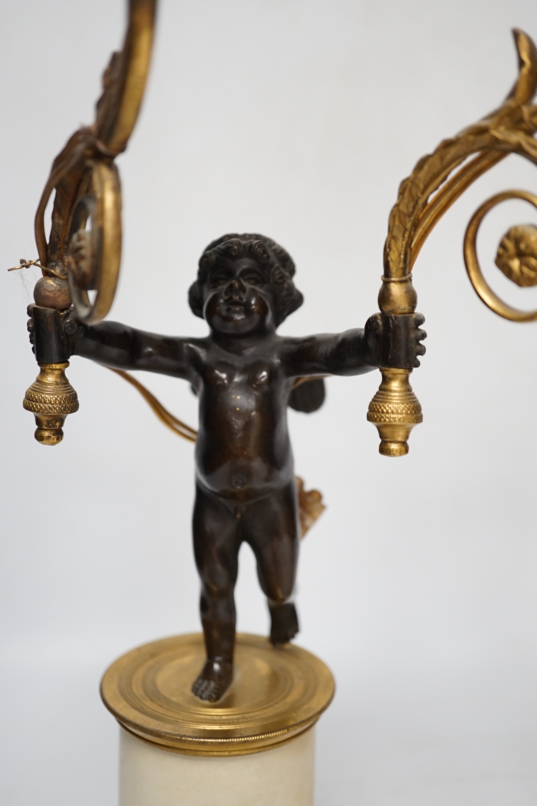 A pair of Louis XVI style bronze, ormolu and alabaster cherub lamps, 42cm high (one a.f.)